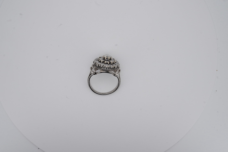 A white metal and diamond cluster set dress ring, with 'wire work' shoulders, size H, gross weight 5.2 grams. Condition - fair to good